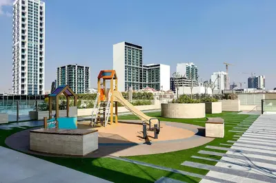 a playground with a slide in a park with tall buildings at Stylish 1BR Apartment in Binghatti Onyx JVC in Dubai