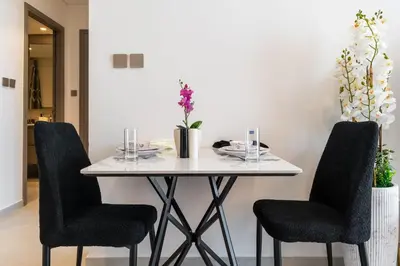 a dining room table with two chairs and a white table at Full Burj Khalifa and Fountain View from All Rooms in Dubai
