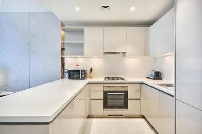 a white kitchen with white cabinets and appliances at STAY BY LATINEM Luxury 1BR Holiday Home CVG 3204 Near Burj Khalifa in Dubai