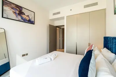 a bedroom with a white bed with blue accents at Burj & Fountain View Retreat in Dubai