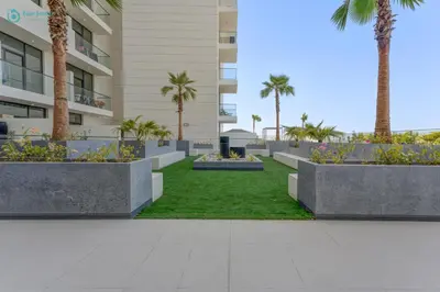 a garden in front of a building with palm trees at Bright & Luxury Studio with Balcony in Al Furjan in Dubai