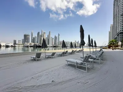 a row of chairs and umbrellas on a beach at Seaside Elegance 1BR Luxury Apartment with Private Beach Access, Emaar Beachfront in Dubai