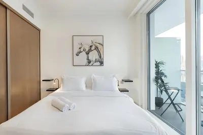a bedroom with a large white bed and a window at ALiving Classy 1BR I Stunning Views I Emaar Palace Beach Residence in Dubai