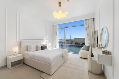 a white bedroom with a bed and a large window at 2BR Canal Front B3, Waterfront Views in Dubai