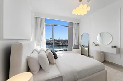 a white bedroom with a large bed and a large window at 2BR Canal Front B3, Waterfront Views in Dubai