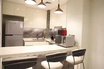 a kitchen with a counter with chairs and a microwave at Brand New Large 2 Bedroom with Burj Khalifa view in Dubai