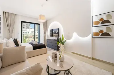 a white bedroom with a bed and a table at Holiday Boulevard - Stylish Upgraded Studio - Designer Touches in JVC in Dubai