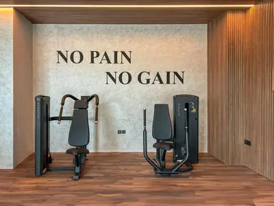 a gym with two exercise bikes and a no pain no gain wall at Holiday Boulevard - Stylish Upgraded Studio - Designer Touches in JVC in Dubai