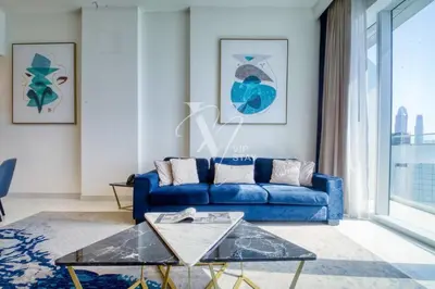 a living room with a blue couch and a glass table at Luxurious 1BR in Palm View with Palm Jumeirah Views in Dubai