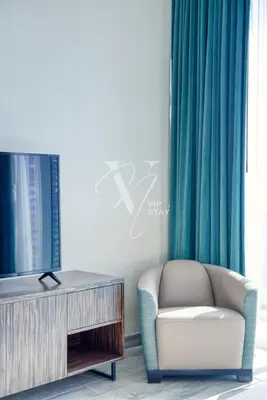 a living room with a chair and a tv at Luxurious 1BR in Palm View with Palm Jumeirah Views in Dubai