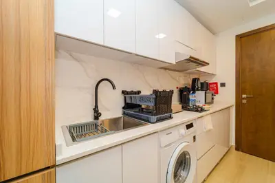 a kitchen with a sink and a washing machine at Elegant JVC Stay Luxury Amid Nature in Dubai