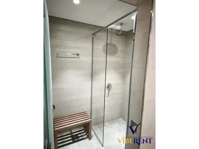 a glass shower with a bench in a bathroom at 2BR Sofa Bed Sleep 6 Furjan in Dubai