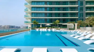 a swimming pool with lounge chairs and a building at Luxury 2BR, Panoramic Sea Views and Beach Access in Dubai