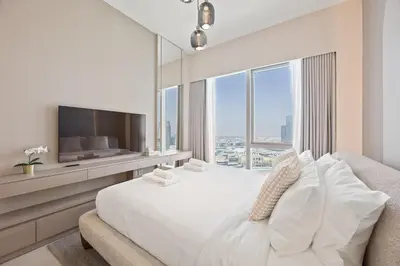 a white bedroom with a large bed and a large window at Elite Escapes - 2 BHK Luxurious - Grande Signature in Dubai
