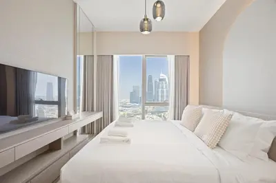 a bedroom with a large white bed and a large window at Elite Escapes - 2 BHK Luxurious - Grande Signature in Dubai