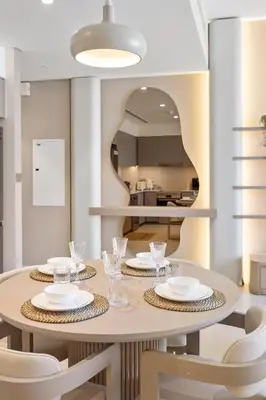 a dining room with a table and chairs and a mirror at Elite Escapes - 2 BHK Luxurious - Grande Signature in Dubai