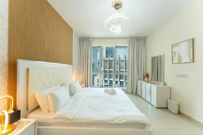 a bedroom with a large white bed and a window at Stand Point Residence by Hogar in Dubai
