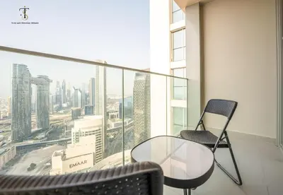 a glass table and chairs in a room with a view at Swanky Suite Forte T1 2BR Downtown in Dubai