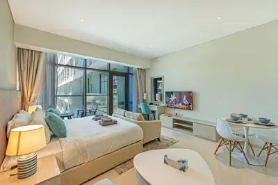 a bedroom with a large bed and a living room at Spacious Studio Beach Access Seven Palm Dubai in Dubai