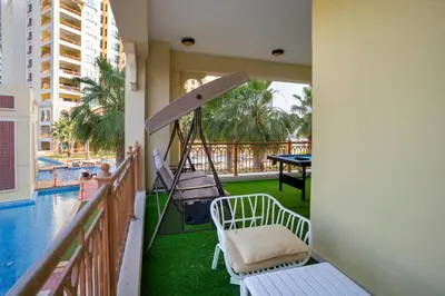 a balcony with a swing and a pool at PJ- Premium Palm Jumeirah Apartment - Beachfront, Pool & Balcony in Dubai