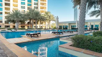 a pool with benches and palm trees in a resort at PJ- Premium Palm Jumeirah Apartment - Beachfront, Pool & Balcony in Dubai