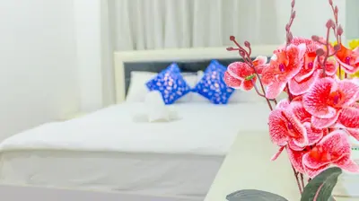 a vase of flowers on a table in a bedroom at 1BHK Holiday Location in Dubai