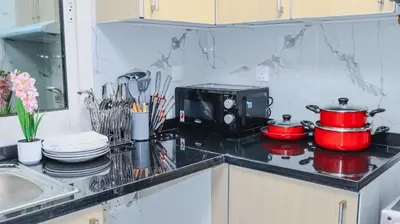 a kitchen counter with a stove with pots and pans at 1BHK Holiday Location in Dubai