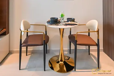 a dining room table with two chairs and a gold table at New Studio In Arjan by Deleguest in Dubai