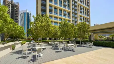 a patio with white chairs and tables and trees at TRPS - Burj Royale, Downtown Dubai - 2BR - Burj Khalifa View - Furnished & Ready in Dubai