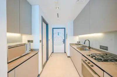 a kitchen with white cabinets and a door to a hallway at Stylish Retreat in Business Bay in Dubai