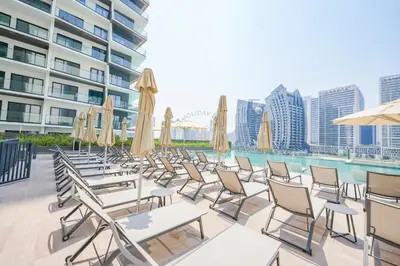 a row of chairs and umbrellas next to a pool at Stylish Retreat in Business Bay in Dubai