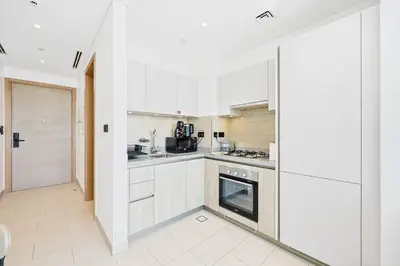 a kitchen with white cabinets and a stove at High-Floor Luxury Spacious 1BR in Sobha Waves in Dubai