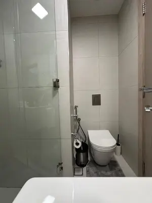 a white bathroom with a toilet and a shower at Cosy Studio - Luma 22 in Dubai