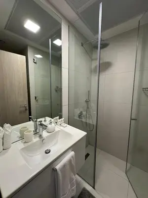 a white bathroom with a sink and a shower at Cosy Studio - Luma 22 in Dubai