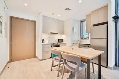 a kitchen with a wooden table and chairs at Charming 1BR with Airy Terrace, Pool and Gym Access in Dubai