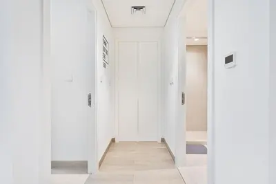 a hallway with white walls and a white door at Charming 1BR with Airy Terrace, Pool and Gym Access in Dubai