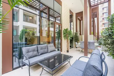 a patio with a couch and chairs on a building at Charming 1BR with Airy Terrace, Pool and Gym Access in Dubai