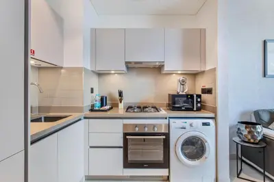 a kitchen with white cabinets and a washer and dryer at STAY BY LATINEM Luxury 1BR Holiday Home CVR B803 Near Burj Khalifa in Dubai