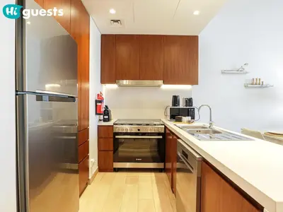 a kitchen with wooden cabinets and a stainless steel refrigerator at HiGuests - Soothing Seaside 2 BR Haven in La Mer in Dubai