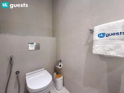 a bathroom with a white toilet and a towel at HiGuests - Soothing Seaside 2 BR Haven in La Mer in Dubai