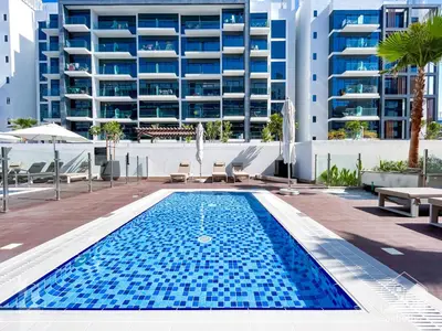 a swimming pool in front of a large building at Charming Studio with Balcony in Azizi Riviera in Dubai