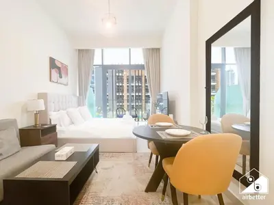 a living room with a bed and a table and chairs at Charming Studio with Balcony in Azizi Riviera in Dubai