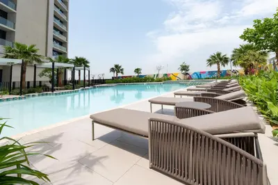 a pool with tables and chairs next to a building at 2 Bedroom Aprtment in Dubai