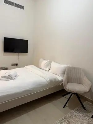 a bedroom with a bed and a chair and a television at EGATE - Studio - 10th Floor - Balcony with a View - 01-1014 in Dubai
