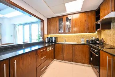 a large kitchen with wooden cabinets and a window at Luxe 2BR with Fountain Views and Walk-Around Terrace in Dubai