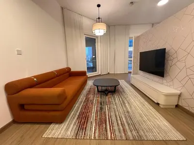 a living room with a couch and a tv at Cozy Studio Apartment in Dubai