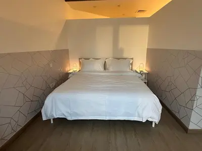 a bedroom with a large white bed with two lamps at Cozy Studio Apartment in Dubai