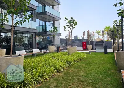 a park in front of a building with benches at Luxurious - Comfy 2BR in Business Bay - City Views in Dubai