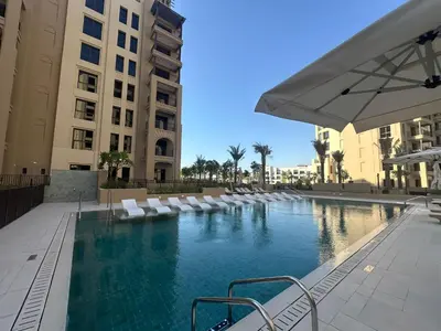 a swimming pool with white lounge chairs and buildings at Brand new apartment next to Burj Al Arb in Dubai
