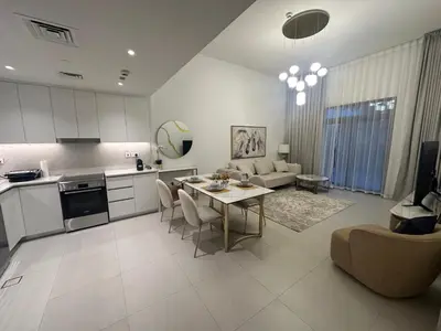 a kitchen and living room with a table and a couch at Brand new apartment next to Burj Al Arb in Dubai